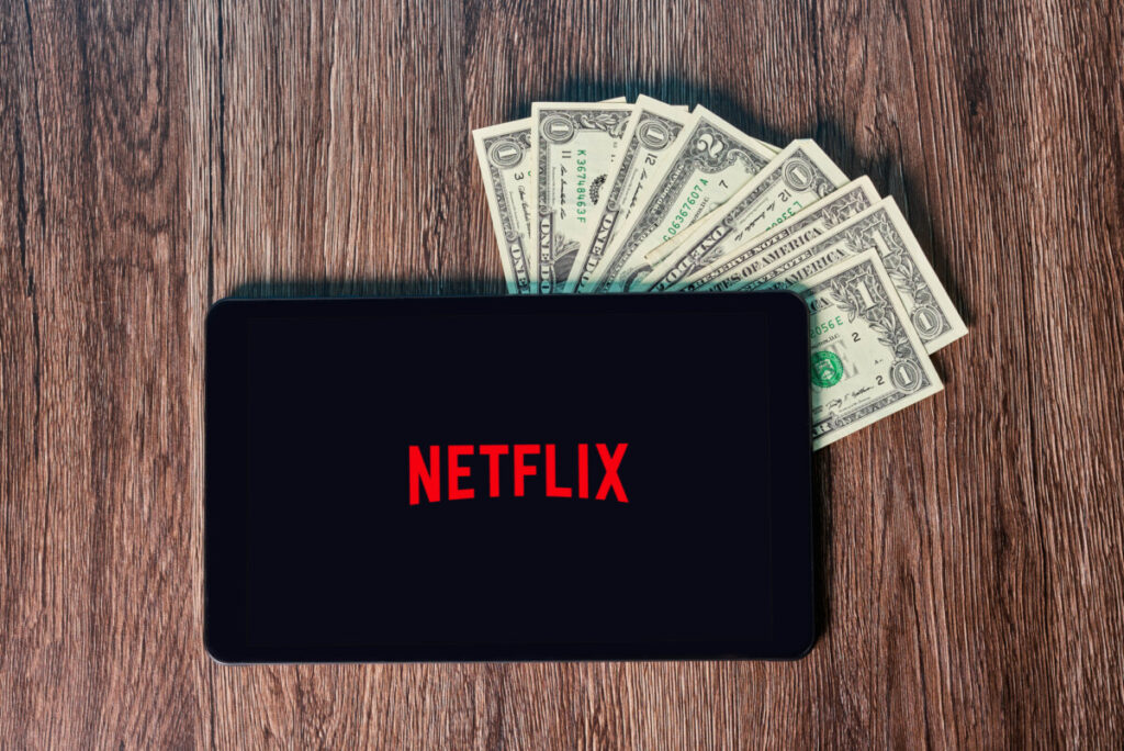 a tablet showing Netflix's logo with money under it